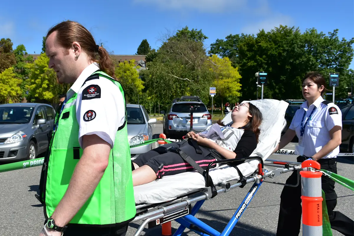 Portfolio: education 2 A woman lying on a stretcher with a man in a green vest